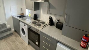A compact kitchen with a washing machine, a stove, and a sink.