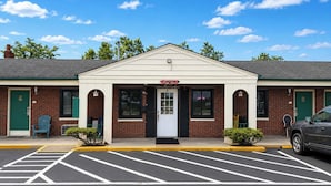 A two-story building with a sign reading 'OFFICE' above the entrance. There are two doors, one on each side of the entrance, and a parking lot in front. - Hillcrest Motel By OYO Aurora IN Near Lawrenceburg (Aurora)