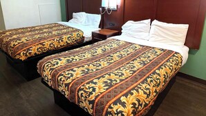 A hotel room with two single beds, a nightstand, a wall-mounted lamp, and a framed picture on the wall. - Hillcrest Motel By OYO Aurora IN Near Lawrenceburg (Aurora)