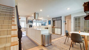 A modern kitchen with a central island, stainless steel appliances, and a dining area with a table and chairs. - 4 Mi to Downtown Plymouth! Bayfront Home w/ Deck (Plymouth)