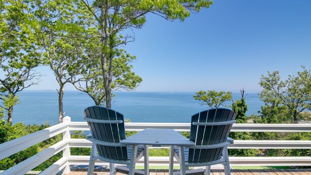 A deck with two Adirondack chairs and a table, overlooking a body of water. - 4 Mi to Downtown Plymouth! Bayfront Home w/ Deck (Plymouth)