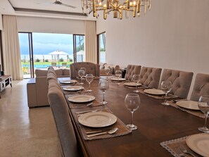A dining room with a long table set for a meal, a sofa, and a view of the outdoors. - Aryan Beach Villa – A Private Family-Friendly Haven in Wadduwa (Wadduwa)