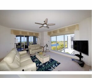 Enjoy the view of the building and water from the comfort of this living room, featuring a sofa, coffee table, and telescope.