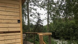 Una terraza de madera con vistas a un área boscosa y un río.