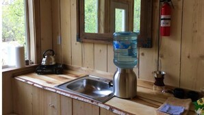Cocina de cabaña de madera con un fregadero, hervidor, dispensador de agua y un extintor.