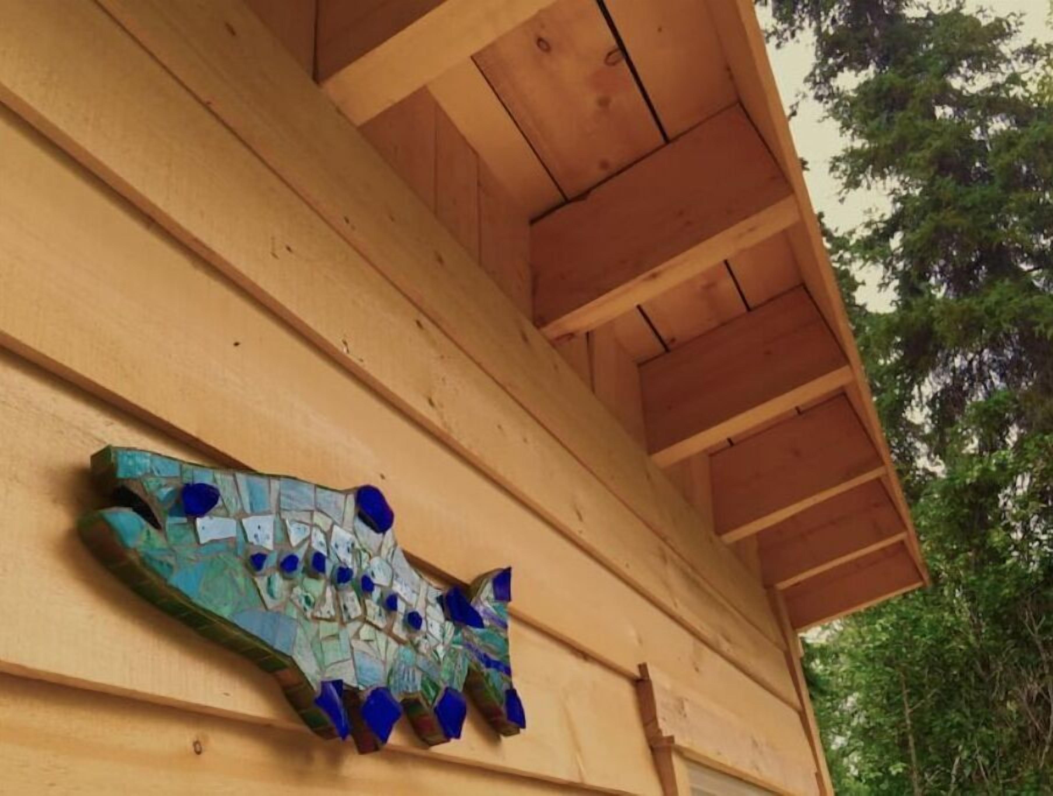 A wooden structure with a sloped roof and a mosaic artwork on the wall.