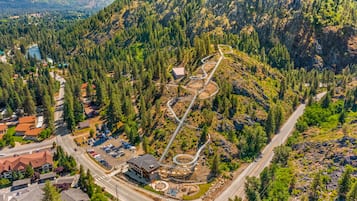 An aerial view of a mountainous area with a winding road, a parking lot, and a building with a red roof.