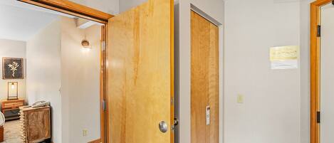 A hallway with wooden doors, a small wooden cabinet, and a framed picture on the wall.