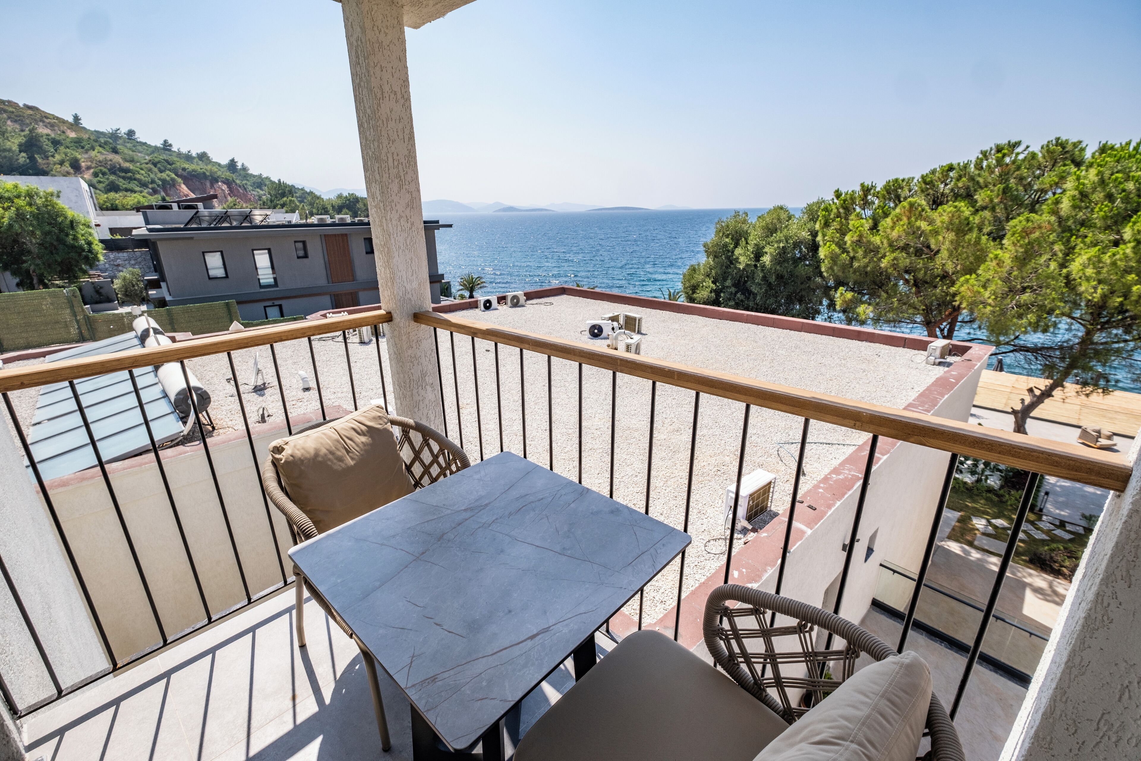 A balcony with a table and chairs, overlooking a body of water and buildings.