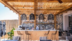 An outdoor bar area with a stone wall, wooden ceiling, and bar stools. - Isolina Bodrum (Bodrum)