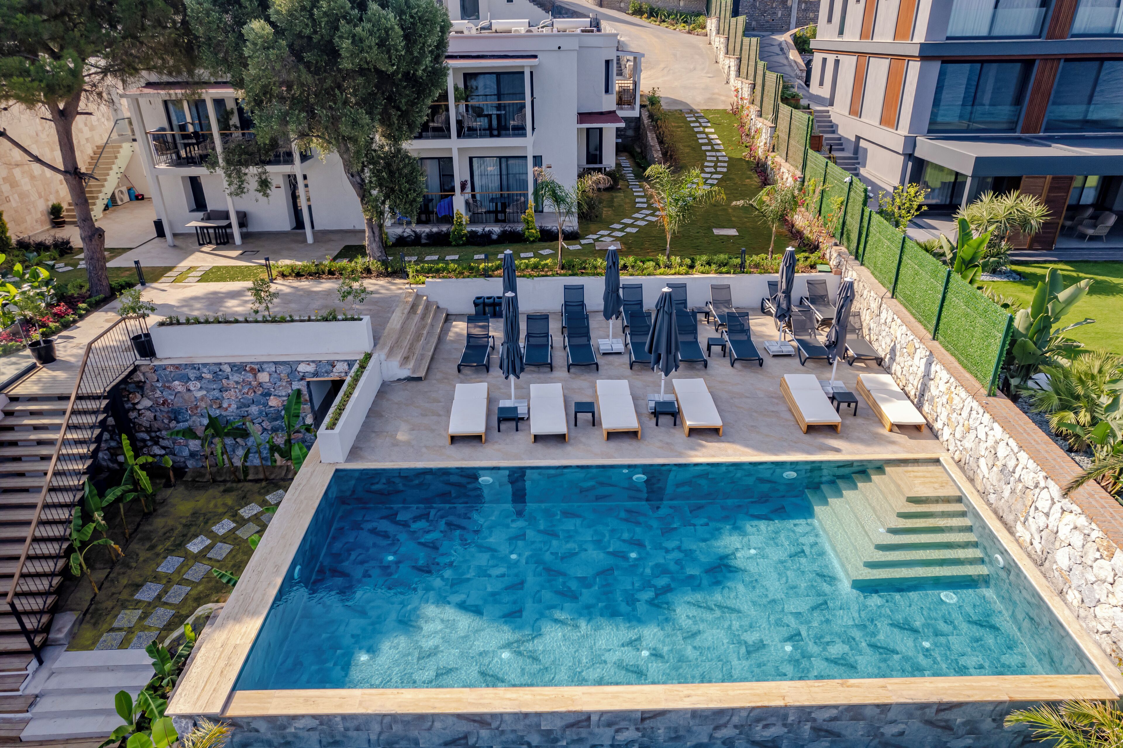 Um hotel moderno com piscina, espreguiçadeiras e um jardim bem cuidado.