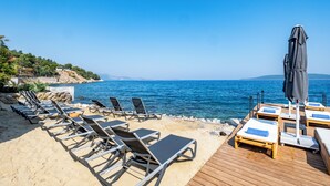 A beach with sun loungers and umbrellas, a wooden deck, and a view of the sea. - Isolina Bodrum (Bodrum)
