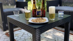 A patio table with a plate of nuts, two beer bottles, and glasses. - Typée, Accueillante et Confortable Maison (Pessac)