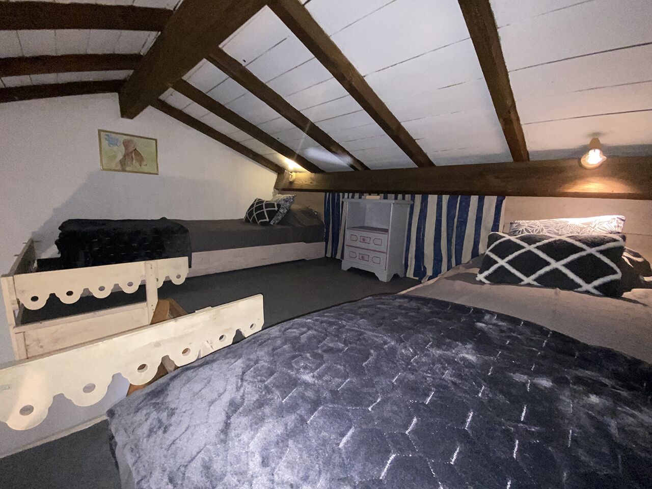 A bedroom with a bunk bed, a single bed, a dresser, and a window with curtains.