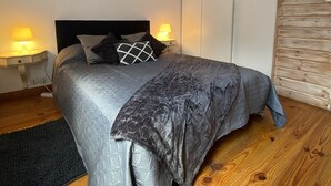 A bedroom with a bed, two bedside lamps, a wooden floor, and a wooden ceiling. - Typée, Accueillante et Confortable Maison (Pessac)