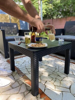Una mesa con un plato de frutos secos, una botella de cerveza y un vaso de cerveza.