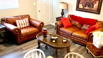 A living room with two brown leather sofas, a coffee table, and a white chair.