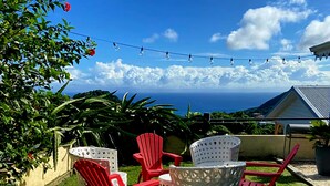 Eine Terrasse mit Gartenmöbeln, Lichterketten und Blick auf den Ozean.