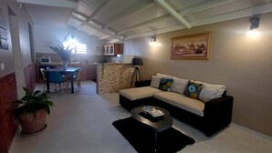 Ein Wohnzimmer mit Sofa, Couchtisch und Essbereich mit Stühlen und Tisch.