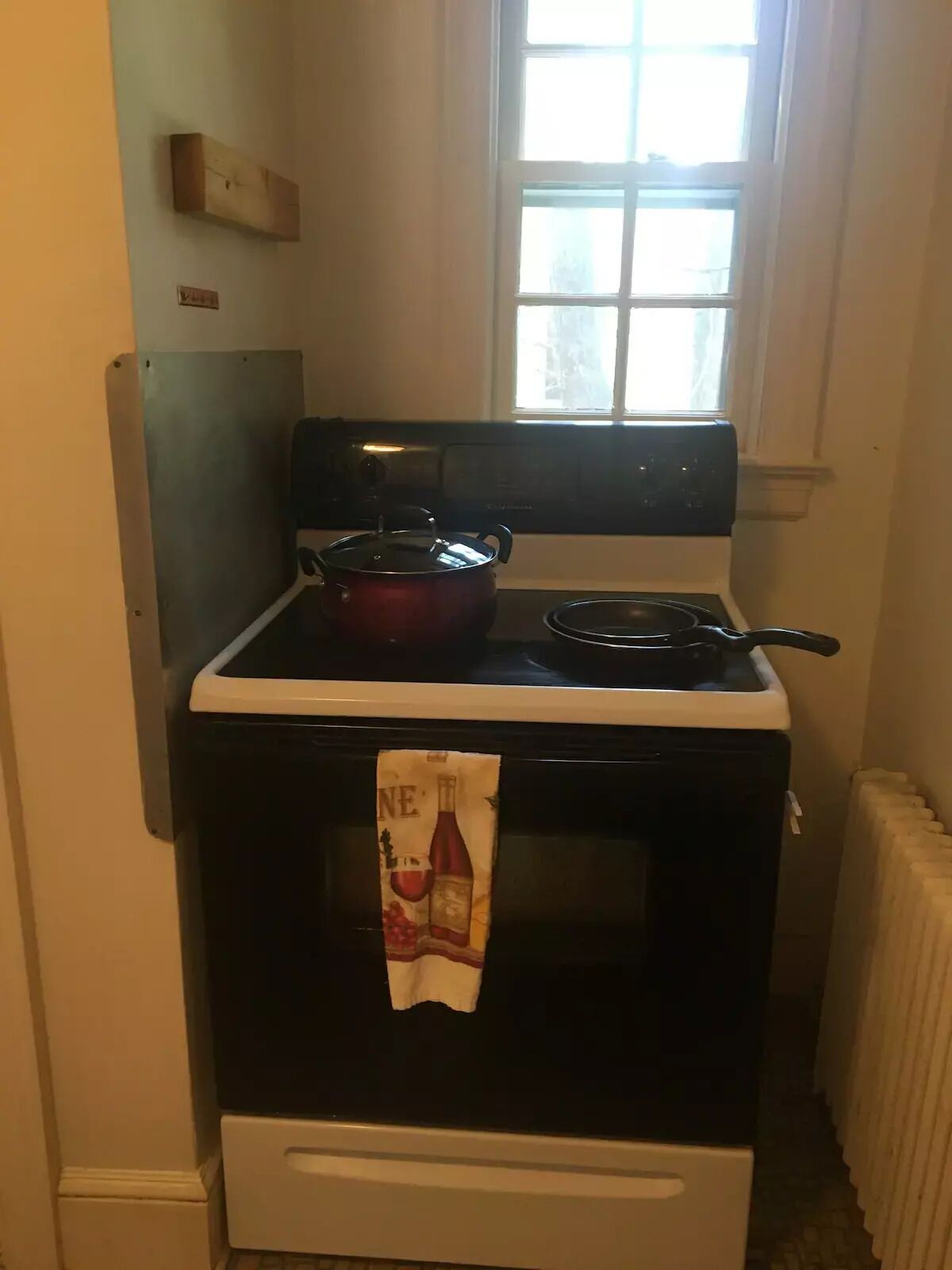 A kitchen with a stove, a red pot, and a frying pan.
