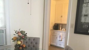 A dining area with a glass table, two grey upholstered chairs, and a decorative fruit arrangement on a small table. - Windsor Lofts 3 (Roanoke)