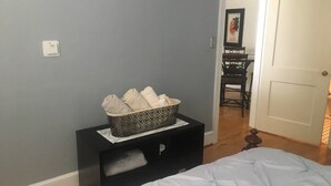 A bedroom with a bed, a black nightstand with a patterned tray, and a gray wall. - Windsor Lofts 4 (Roanoke)