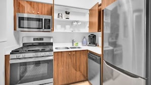 Une cuisine compacte équipée d’un réfrigérateur en acier inoxydable, d’un four à micro-ondes, d’une cuisinière et d’un lave-vaisselle.