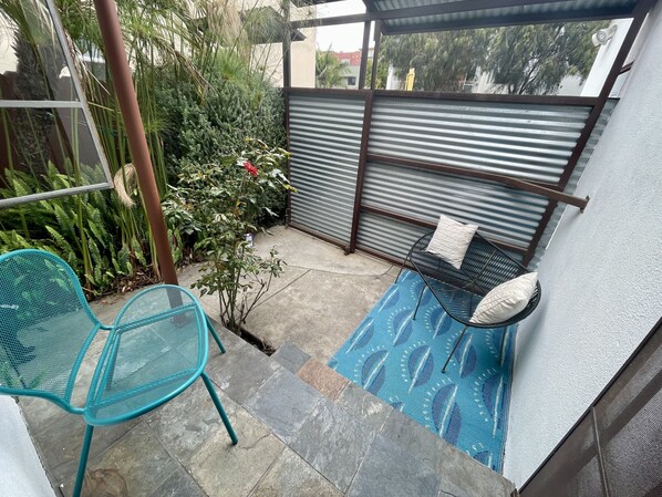 Relax in this serene outdoor space with a seating area, featuring a bench and chair, surrounded by lush greenery.