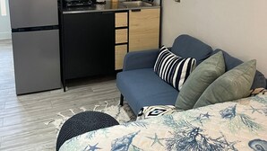 A compact living space with a kitchenette, a sofa with patterned bedding, and a small dining table. - Charming Isla Verde Studio (Carolina)