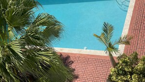 A rectangular swimming pool with a blue interior, surrounded by a red brick patio. - Charming Isla Verde Studio (Carolina)