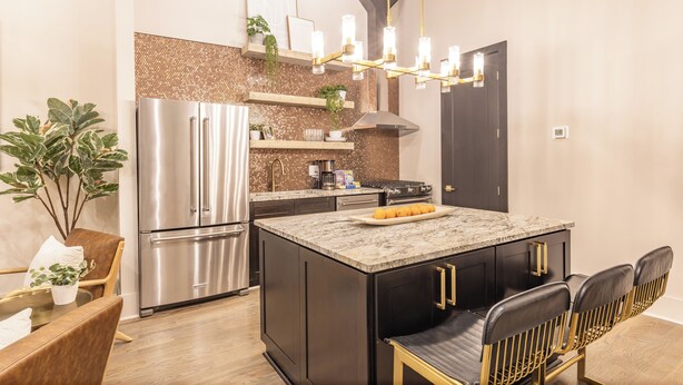 Una cucina moderna con frigorifero in acciaio inossidabile, isola con piano in marmo e forno integrato.
