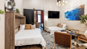 Una moderna camera d'albergo con due letti, un divano, un tavolino e una televisione.