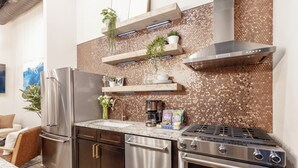 Una cucina moderna con elettrodomestici in acciaio inossidabile, mobili in legno e una parete di fondo rivestita con piastrelle esagonali.