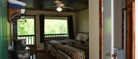 A bedroom with two beds, a ceiling fan, and a view of the outdoors.