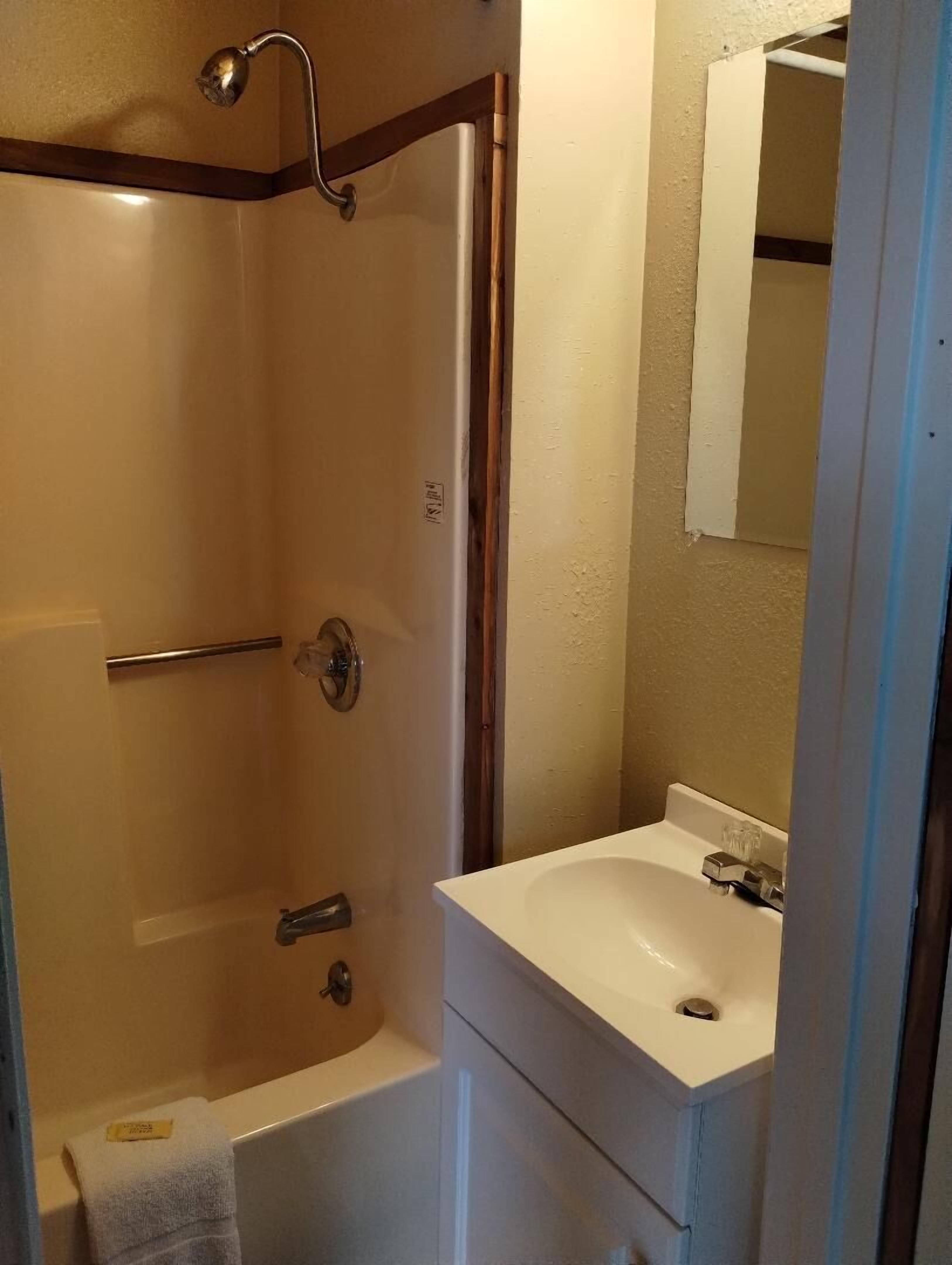 Tina con regadera, toallas, papel de baño 