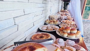 Una mesa de buffet con diversas opciones de repostería, incluyendo pasteles y dulces, dispuestas en platos.