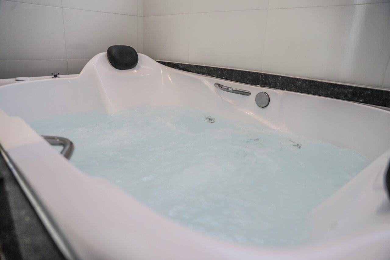 Une baignoire blanche avec un siège noir et un seul robinet.