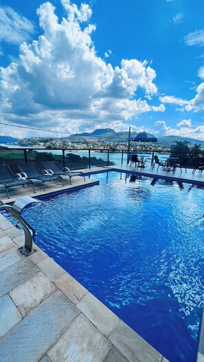 A swimming pool with lounge chairs and a view of a mountainous landscape. - Pousada Capitólio (Capitólio)