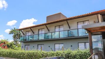 A two-story building with a balcony, a car parked in front, and a clear blue sky.