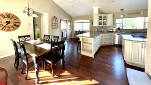 Une cuisine spacieuse dotée d’un grand îlot central, de planchers en bois et d’un ventilateur de plafond.