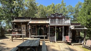 Un bar de style rustique, avec une façade en bois, une véranda dotée de bancs et une enseigne indiquant « Hôtel de qualité supérieure ».
