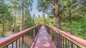 Un pont en bois avec des garde-corps métalliques, situé dans une zone boisée.