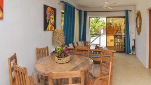 Un coin repas avec une table ronde en bois, des chaises en bois et un panier tressé rempli de fleurs.