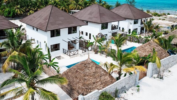 Un complexe hôtelier comprenant plusieurs bâtiments blancs, une piscine et donnant sur la plage.