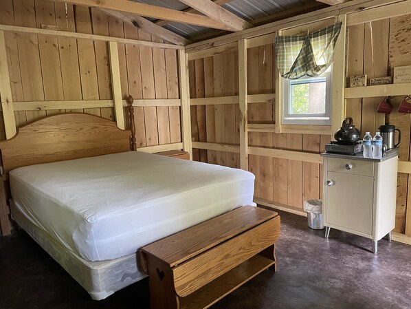 Een houten kamer met een bed, een klein kastje en een raam met gordijnen.
