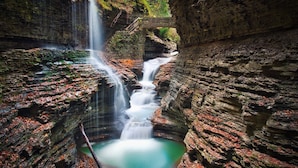 Ein Wasserfall stürzt in einen Teich, umgeben von felsigen Klippen.