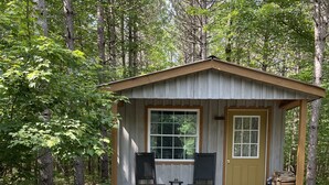 Eine rustikale Holzhütte mit Veranda, zwei Schaukelstühlen und einem Feuerkorb.