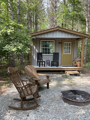 Un chalet rustique doté d’une véranda, de deux fauteuils à bascule et d’un foyer.