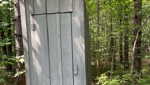 Ein kleines, hölzernes Gartenhaus in einem bewaldeten Gebiet.