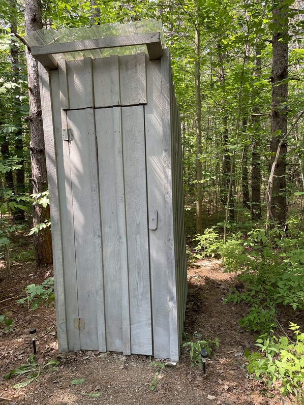 Ein kleines, hölzernes Gartenhaus in einem bewaldeten Gebiet.